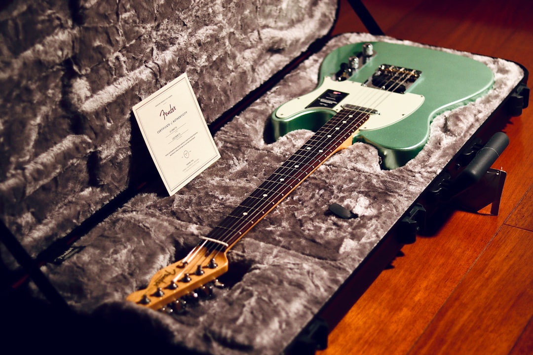 a green electric guitar in a case on a wooden floor